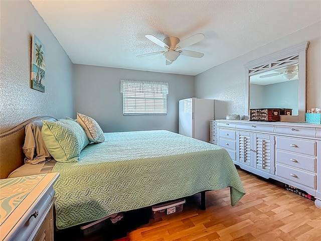 200 Country Club Dr Unit 202, Largo, FL 33771 - bedroom with light wood-type flooring, freestanding refrigerator, ceiling fan, and a textured wall