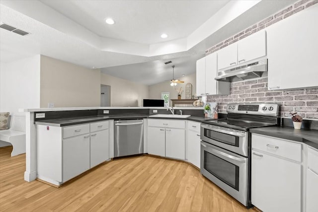 6051 65th Ave N, Pinellas Park, FL 33781 - kitchen with appliances with stainless steel finishes, under cabinet range hood, a peninsula, dark countertops, and light wood-style flooring