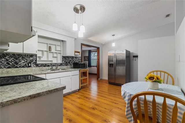 4318 Mesa Dr, New Port Richey, FL 34653 - kitchen featuring appliances with stainless steel finishes, tasteful backsplash, a textured ceiling, decorative light fixtures, and light wood-style floors