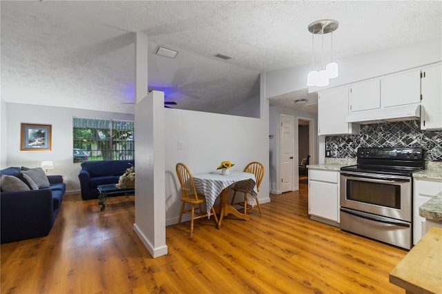 4318 Mesa Dr, New Port Richey, FL 34653 - kitchen featuring stainless steel electric stove, under cabinet range hood, light countertops, lofted ceiling, and open floor plan