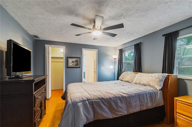 4318 Mesa Dr, New Port Richey, FL 34653 - bedroom with a walk in closet, a textured ceiling, ceiling fan, a closet, and parquet flooring