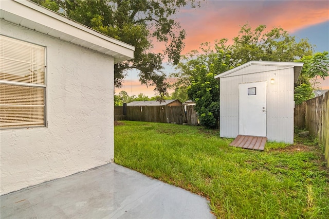 4318 Mesa Dr, New Port Richey, FL 34653 - yard at dusk with a fenced backyard, a patio area, and a shed