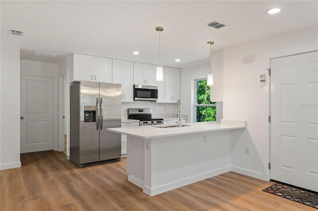 10219 Huntley St, New Port Richey, FL 34654 - kitchen with stainless steel appliances, a peninsula, light wood-style flooring, white cabinetry, and recessed lighting