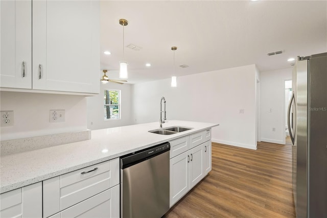 10219 Huntley St, New Port Richey, FL 34654 - kitchen with stainless steel appliances, white cabinets, light wood-style floors, pendant lighting, and a peninsula