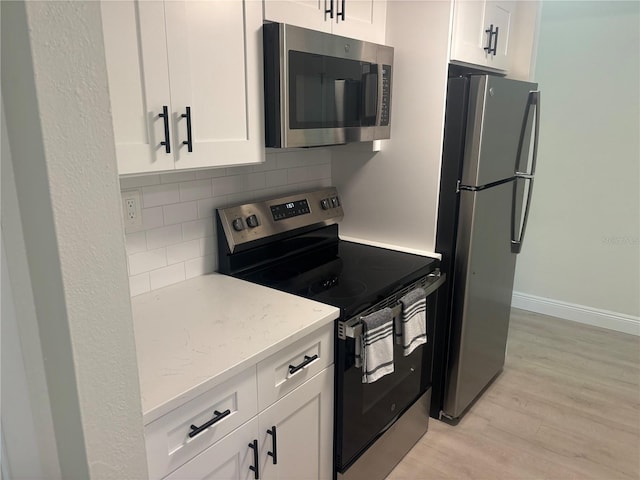 3640 41st Ln S Unit F, Saint Petersburg, FL 33711 - kitchen with stainless steel appliances, light wood-style floors, decorative backsplash, and white cabinets