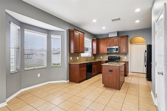 7509 Tangle Bend Dr, Gibsonton, FL 33534 - kitchen with black appliances, arched walkways, tasteful backsplash, a kitchen island, and light tile patterned floors