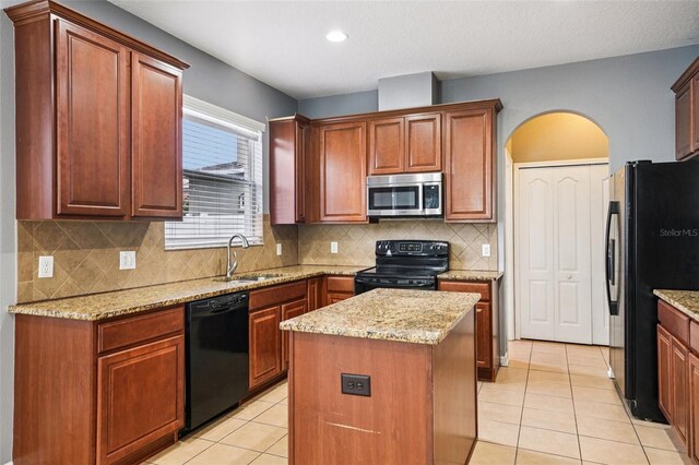 7509 Tangle Bend Dr, Gibsonton, FL 33534 - kitchen with black appliances, light tile patterned floors, a center island, light stone countertops, and arched walkways