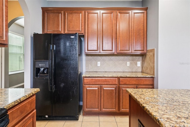 7509 Tangle Bend Dr, Gibsonton, FL 33534 - kitchen featuring black fridge, arched walkways, tasteful backsplash, light stone counters, and light tile patterned floors