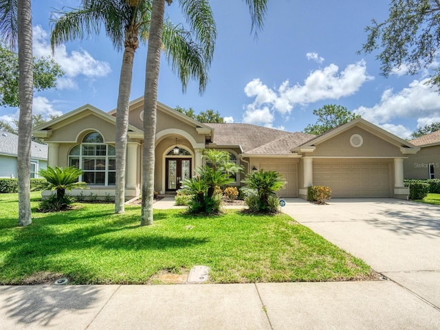 4335 Clairidge Way, Palm Harbor, FL 34685 - mediterranean / spanish-style house with french doors, stucco siding, a garage, driveway, and a front yard