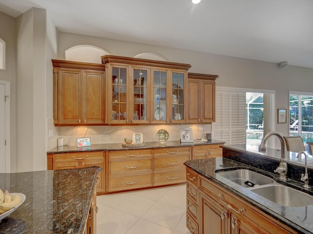 4335 Clairidge Way, Palm Harbor, FL 34685 - kitchen with brown cabinets, glass insert cabinets, light tile patterned floors, and dark stone countertops