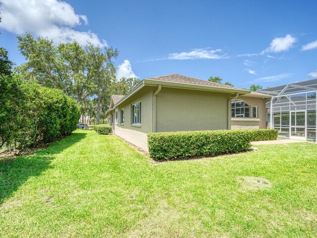 4335 Clairidge Way, Palm Harbor, FL 34685 - view of side of home featuring stucco siding, a lawn, and glass enclosure