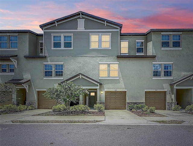 4567 Tuscan Loon Dr, Tampa, FL 33619 - view of front of property with a garage, stucco siding, concrete driveway, and stone siding