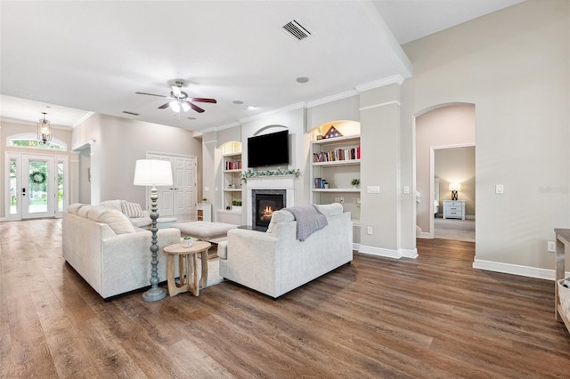 5823 Terncrest Dr, Lithia, FL 33547 - living room with dark wood-type flooring, a glass covered fireplace, ceiling fan, arched walkways, and built in shelves