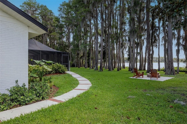 19209 Crooked Ln, Lutz, FL 33548 - view of grassy yard featuring an outdoor fire pit, a water view, glass enclosure, and a patio