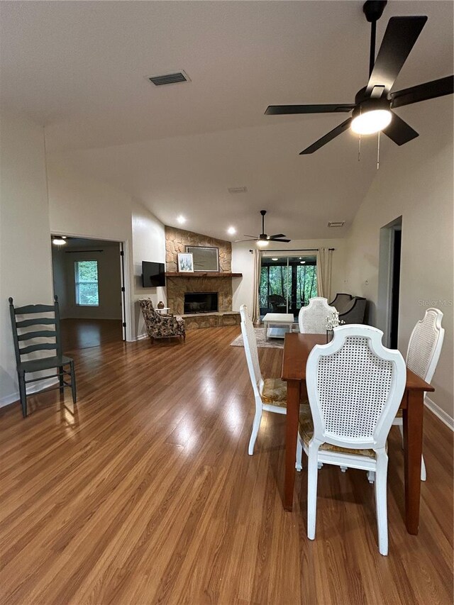 17631 Grove View Dr, Lutz, FL 33549 - dining room featuring a ceiling fan, light wood finished floors, a stone fireplace, healthy amount of natural light, and lofted ceiling