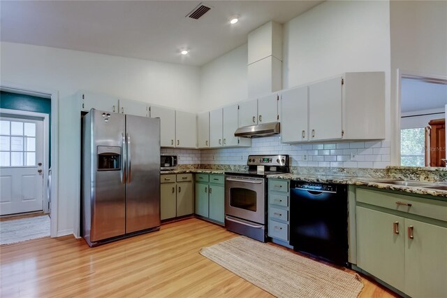 17631 Grove View Dr, Lutz, FL 33549 - kitchen featuring appliances with stainless steel finishes, under cabinet range hood, tasteful backsplash, light wood-style floors, and a towering ceiling