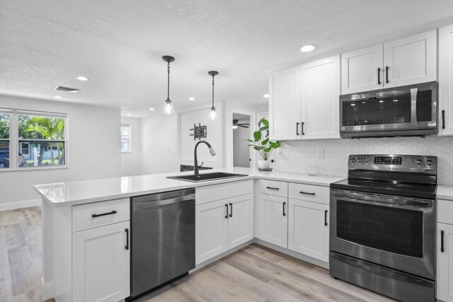 6442 Sutherland Ave, New Port Richey, FL 34653 - kitchen with appliances with stainless steel finishes, a peninsula, light countertops, white cabinetry, and tasteful backsplash