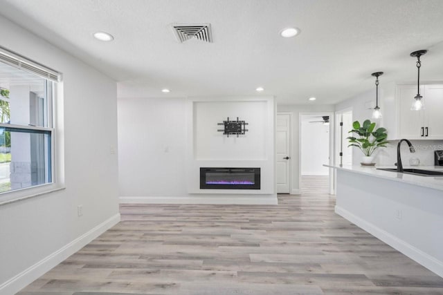 6442 Sutherland Ave, New Port Richey, FL 34653 - unfurnished living room featuring recessed lighting, a glass covered fireplace, light wood finished floors, and ceiling fan