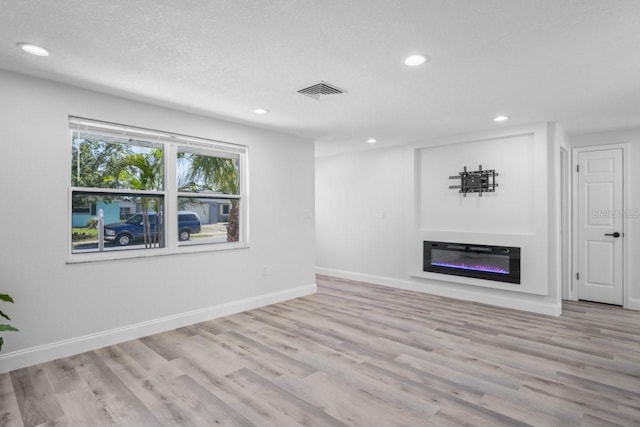 6442 Sutherland Ave, New Port Richey, FL 34653 - unfurnished living room with recessed lighting, wood finished floors, a glass covered fireplace, and a textured ceiling
