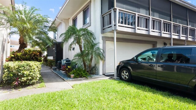 1851 Bough Ave Unit A, Clearwater, FL 33760 - view of side of home with a garage, a balcony, stucco siding, and a lawn