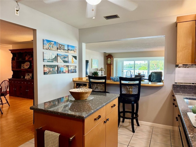 100 Bluff View Dr Unit 114C, Belleair Bluffs, FL 33770 - kitchen featuring a ceiling fan, dark stone countertops, and light tile patterned flooring