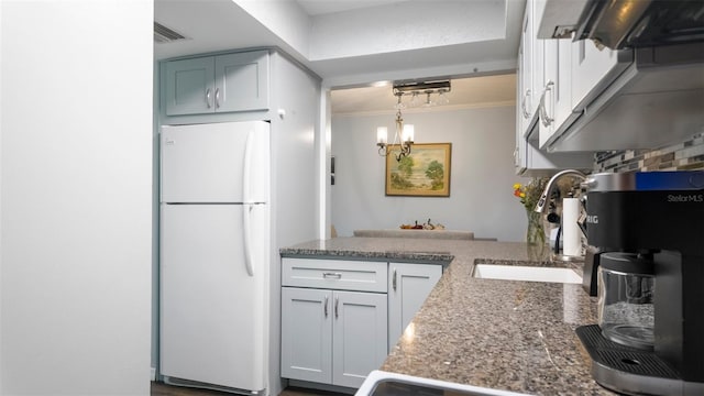 2941 Lichen Ln Unit B, Clearwater, FL 33760 - kitchen with freestanding refrigerator, crown molding, a peninsula, a chandelier, and light stone counters