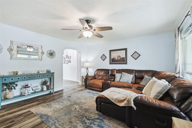 3628 Dellefield St, New Port Richey, FL 34655 - living room featuring arched walkways, a ceiling fan, dark wood-type flooring, baseboards, and a textured ceiling