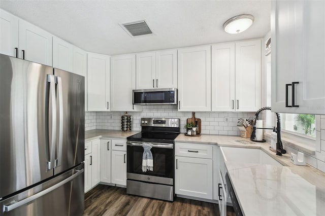3628 Dellefield St, New Port Richey, FL 34655 - kitchen with appliances with stainless steel finishes, light stone counters, white cabinets, tasteful backsplash, and a textured ceiling