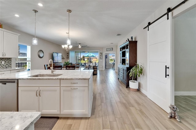 7116 Estero Ct, Apollo Beach, FL 33572 - kitchen with stainless steel dishwasher, a barn door, light wood-type flooring, white cabinetry, and open floor plan