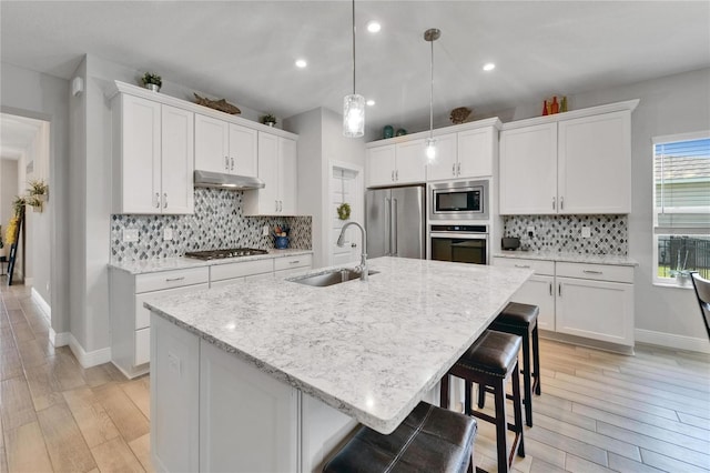 7116 Estero Ct, Apollo Beach, FL 33572 - kitchen with appliances with stainless steel finishes, under cabinet range hood, backsplash, white cabinetry, and recessed lighting