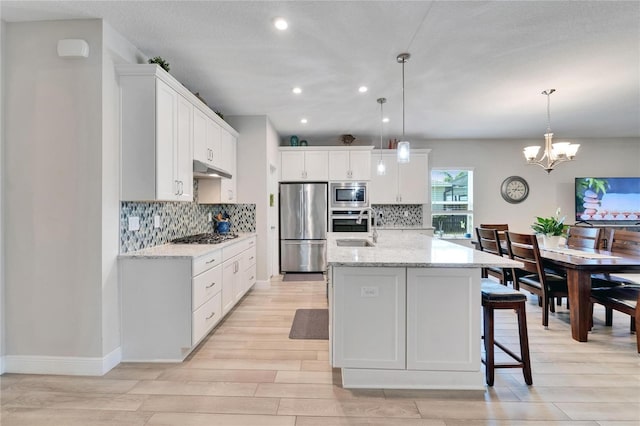 7116 Estero Ct, Apollo Beach, FL 33572 - kitchen with appliances with stainless steel finishes, light wood-type flooring, tasteful backsplash, a chandelier, and recessed lighting