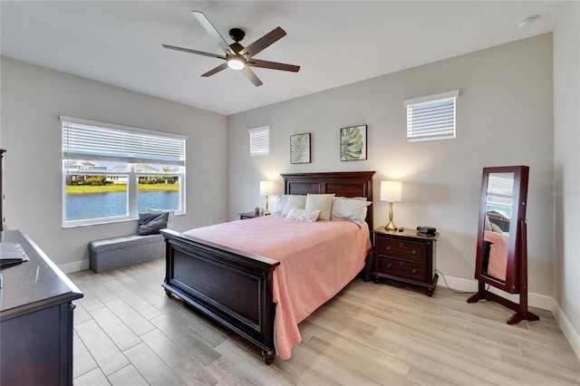 7116 Estero Ct, Apollo Beach, FL 33572 - bedroom with light wood-type flooring, multiple windows, a ceiling fan, and a water view
