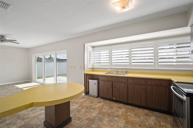 6841 Mitchell Cir, Tampa, FL 33634 - kitchen featuring stainless steel range with electric cooktop, stone finish floors, light countertops, a ceiling fan, and a textured ceiling