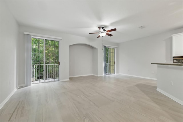 27563 Pleasure Ride Loop, Wesley Chapel, FL 33544 - unfurnished living room featuring ceiling fan, arched walkways, and healthy amount of natural light