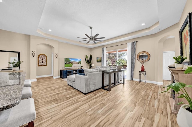 32624 Summerglade Dr, Wesley Chapel, FL 33545 - living room with arched walkways, a tray ceiling, ceiling fan, light wood finished floors, and recessed lighting