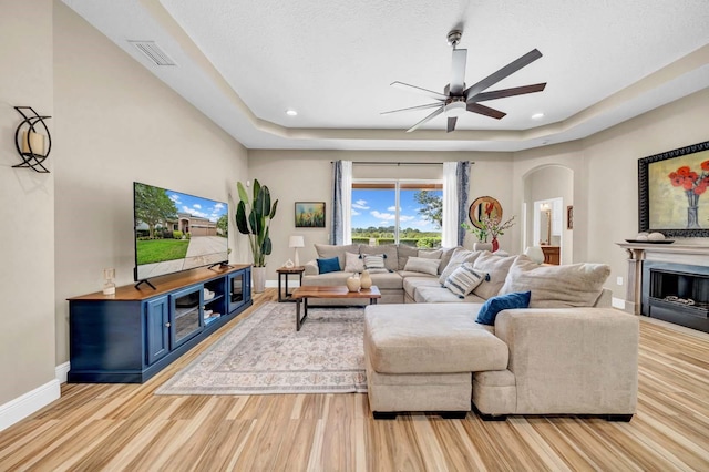 32624 Summerglade Dr, Wesley Chapel, FL 33545 - living area with arched walkways, ceiling fan, light wood-style flooring, a raised ceiling, and recessed lighting