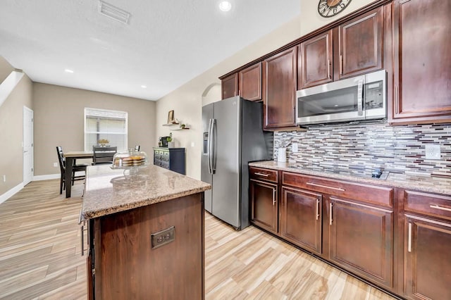 32624 Summerglade Dr, Wesley Chapel, FL 33545 - kitchen featuring stainless steel appliances, light wood-type flooring, a center island, decorative backsplash, and recessed lighting
