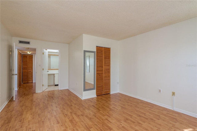 2650 Countryside Blvd Unit C204, Clearwater, FL 33761 - unfurnished bedroom with light wood-style floors, a textured ceiling, a closet, and connected bathroom