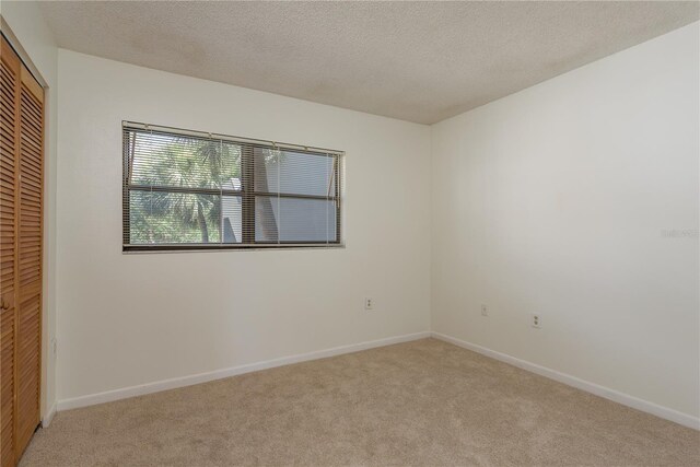 2650 Countryside Blvd Unit C204, Clearwater, FL 33761 - unfurnished bedroom with light carpet, a closet, and a textured ceiling