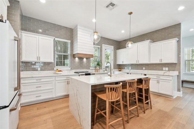 238 7th Ave S, Safety Harbor, FL 34695 - kitchen featuring white refrigerator, decorative backsplash, light wood-type flooring, a kitchen island with sink, and recessed lighting