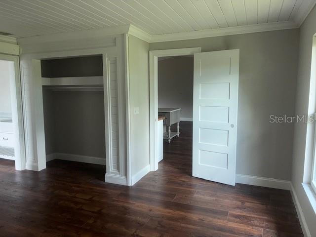 8033 55th St E, Palmetto, FL 34221 - unfurnished bedroom featuring crown molding, a closet, and dark wood finished floors