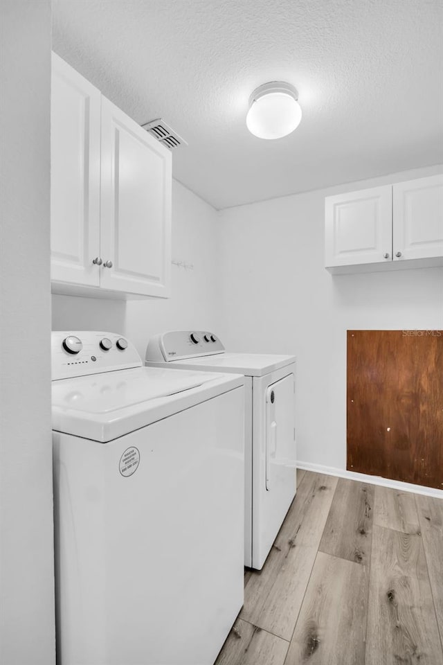 1715 Larabie Ct, Brandon, FL 33511 - washroom with cabinet space, washing machine and clothes dryer, light wood-style floors, and a textured ceiling