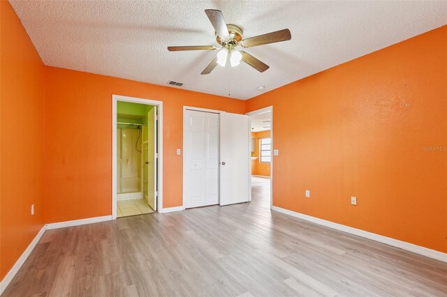 7470 Canterbury St, Spring Hill, FL 34606 - unfurnished bedroom with wood finished floors, a textured ceiling, a closet, connected bathroom, and ceiling fan
