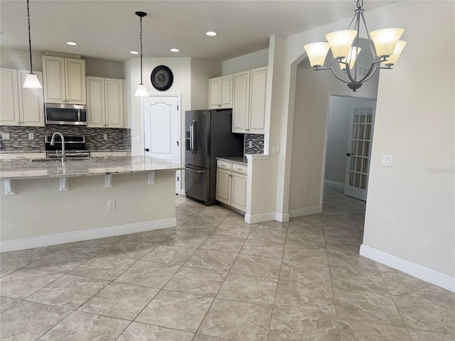 5082 Inshore Landings Dr, Apollo Beach, FL 33572 - kitchen with appliances with stainless steel finishes, tasteful backsplash, cream cabinets, a chandelier, and recessed lighting