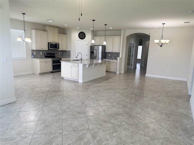 5082 Inshore Landings Dr, Apollo Beach, FL 33572 - kitchen featuring stainless steel appliances, decorative backsplash, arched walkways, a kitchen island with sink, and recessed lighting