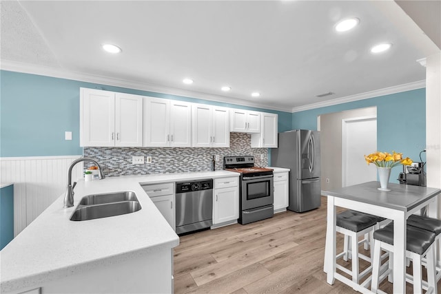 832 Birdie Way, Apollo Beach, FL 33572 - kitchen with appliances with stainless steel finishes, white cabinets, crown molding, wainscoting, and light wood-style floors