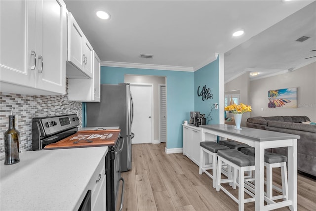 832 Birdie Way, Apollo Beach, FL 33572 - kitchen featuring stainless steel appliances, ornamental molding, white cabinets, backsplash, and light wood-style flooring
