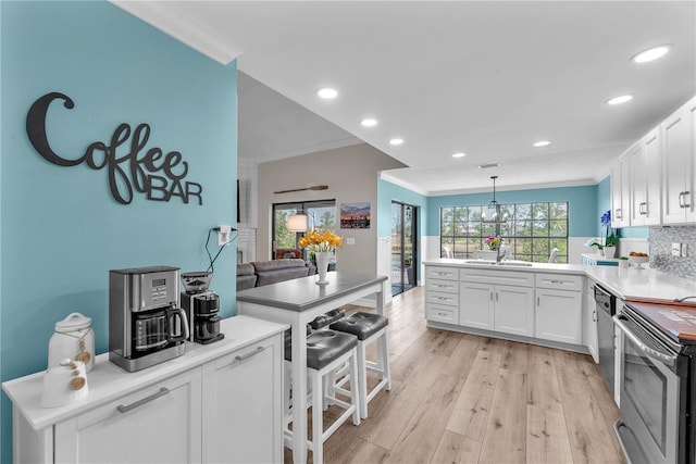 832 Birdie Way, Apollo Beach, FL 33572 - kitchen featuring crown molding, stainless steel appliances, a peninsula, white cabinetry, and light wood finished floors