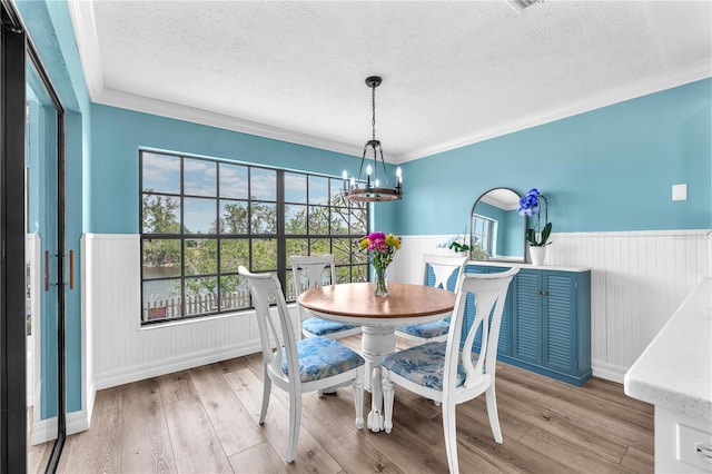 832 Birdie Way, Apollo Beach, FL 33572 - dining space featuring wainscoting, a textured ceiling, a chandelier, light wood-style floors, and crown molding