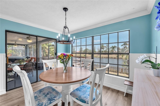 832 Birdie Way, Apollo Beach, FL 33572 - dining space featuring plenty of natural light, a textured ceiling, light wood finished floors, crown molding, and a water view